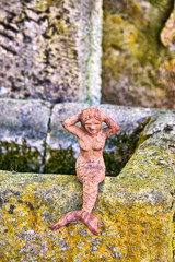 Little mermaid on a natural stone as a garden decoration.