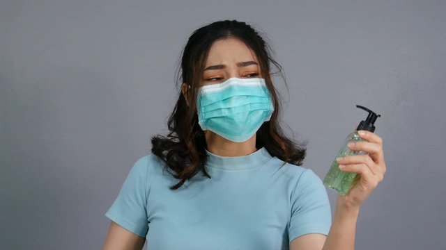 woman in a medical mask(surgical mask) holding alcohol gel with middle finger fuck sign hand gesture, coronavirus protection