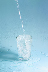 Naklejka na ściany i meble splashing clean water in glass on pastel background