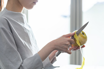 部屋の中でりんごの皮を剥く若い女性の手元