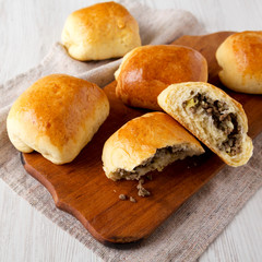 Home-baked Beef Russian Bierocks on a rustic wooden board on a white wooden background, side view. Copy space.