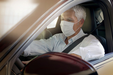 Man driving car and wearing face mask during COVID19 pandemic
