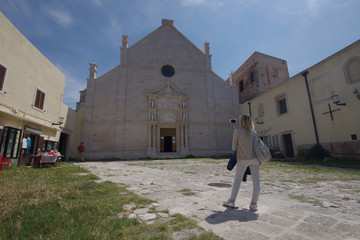 A tourist photographs the Sanctuary of Santa Maria a Mare, an 11th century Romanesque church. Island of San Nicola, archipelago of the Tremiti Islands - Adriatic Sea - Italy