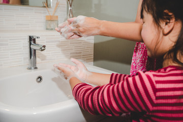 Mom shows daughter proper way to wash hands.