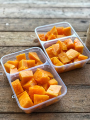 Papaya slices on the plastic boxes on vintage table with natural light , Fruit for diet. healthy food and concept. 