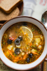 Ceramic plate with soup solyanka, russian hodgepodge soup with olives and lemon