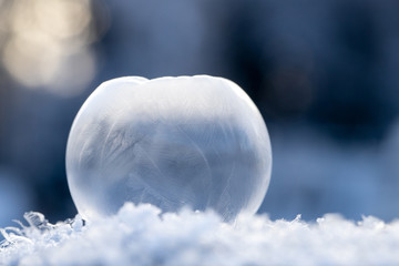 Eine freigestellte vereiste apfelf&ouml;rmige Seifenblase auf Schnee mit ausgepr&auml;gter kristalliner Struktur