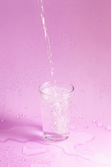 Naklejka na ściany i meble splashing clean water in glass on pastel background.