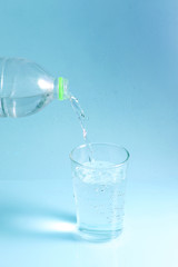 pouring water in glass on pastel background