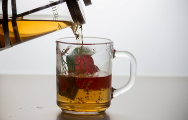 A teapot with tea is poured into a mug