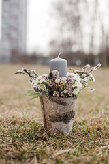 Easter composition with candles and fresh flowers on a grass background