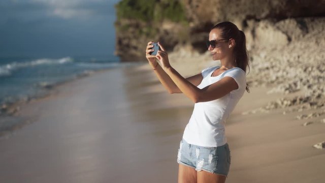 Positive young beautiful girl tourist in casual clothes takes pictures