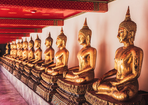 A line of Golden Buddha sitting statues at Wat Pho Buddhist temple, Bangkok, Thailand.
