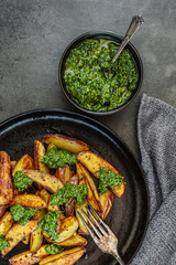Kartoffelspalten mit Pesto aus Kohlrabiblättern auf einem dunklen Hintergrund