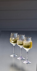 three glasses of fresh golden delicious riesling white wine in a line
