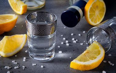 shot of tequila with lemon slices with salt on a gray background, a strong alcoholic drink,