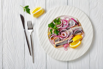 Fototapeta na wymiar Marinated herring fillet with red onion and lemon