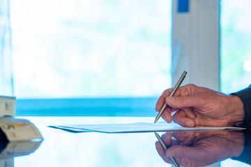 Man signs a document form with a ballpoint pen in the office