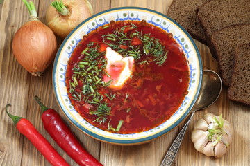 Borsch with sour cream, garlic and hot pepper on a wooden table
