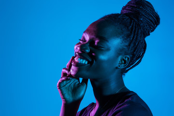 Portrait of young pretty african woman possing in neon light background. Skin care concept.