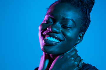 Portrait of young pretty african woman possing in neon light background. Skin care concept.
