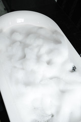 filled white bubble bath with marble walls