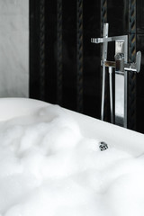 filled white bubble bath with marble walls