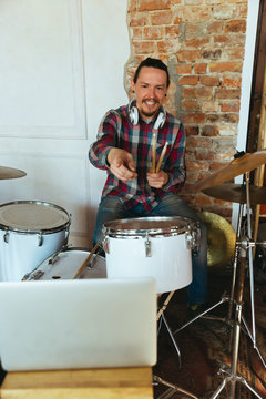 Caucasian musician playing drumms during online concert at home isolated and quarantined. Using camera, laptop, streaming, recording courses. Concept of art, support, music, hobby, education.