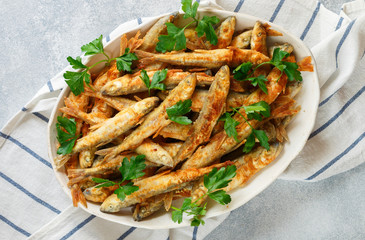 Fried smelt. Delicious small fish with fresh parsley in a white plate. Gourmet appetizer. Selective...