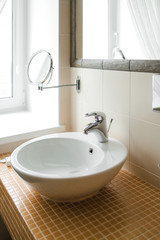 oval white sink in the bathroom on small red tiles in the form of squares