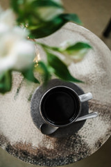a mug of black coffee and fresh flowers on the tea table in the hotel room