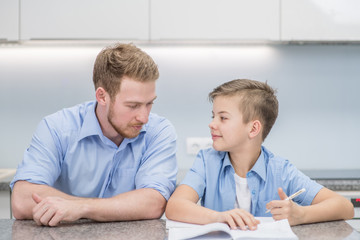 Father helps son do schoolwork at home. Family relationship