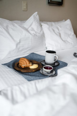 croissant and coffee on the bed in the hotel room
