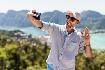 Handsome young man make video call on the phone enjoying the view in phi phi island view point....