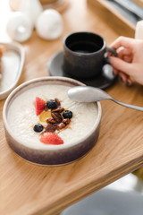 porridge and granola with nuts and berries in a plate on a wooden table
