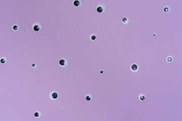 A lot of monster eyes on a light purple background in a minimalistic modern pattern style. Flat lay, top view.