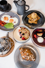 many different dishes in dark plates on a white table