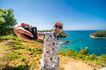 Travel young man standing take a photo with smartphone and see beautiful scenery landscape nature view on rock mountain in phuket thailand.