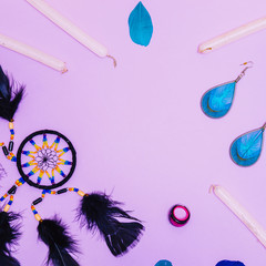Dreamcatcher, glittering candles, ring and feathers on a light purple or lilac background with...