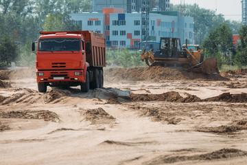 Fototapeta na wymiar orange dump truck truck at a construction site transports sand