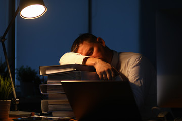 Portrait of hardworking businessman sleeping on big pile of important paper folder full of...
