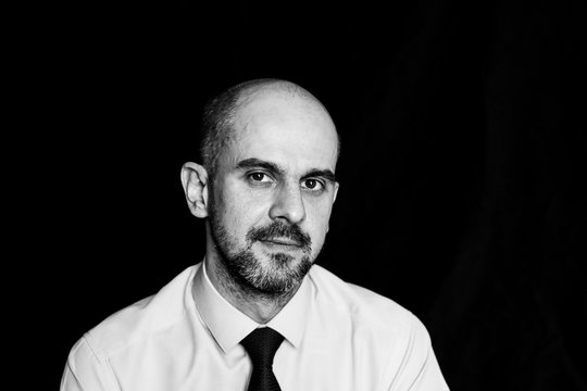 portrait of a serious sad bald man, black and white photo on a black background
