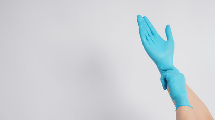 Hand is pulling blue latex gloves on white background.