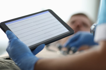 Close-up of doctor holding tablet with graphic. Modern medicine and technology. Medical worker in protective gloves. Ecg and cardiology appointment concept
