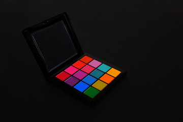 Palette of multicolored eyeshadows on a black background. Space for text