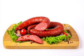
sausage on a cutting board with herbs and vegetables white background