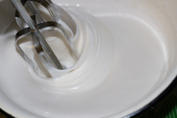 Blender mixing white cream in bowl close up 