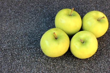 Yellow apples on a gray background. Row of green with one red apple among them on gray background. 4 Thinking out of the box concept. ripe green apples stone table background top view space for text