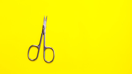 Manicure tool on a yellow background. Steel little scissors. Hand and nail care, manicure. Cosmetic...