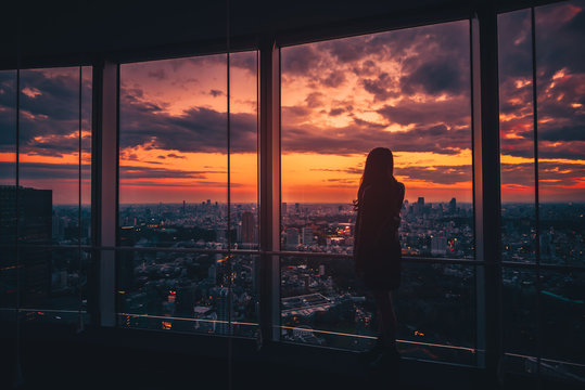 Rear view of Traveler woman looking Tokyo Skyline and view of skyscrapers on the observation deck at sunset in Japan. Vintage tone